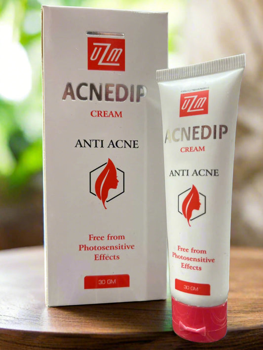 Acnedip anti-acne cream packaging with tube and box on a wooden surface.
