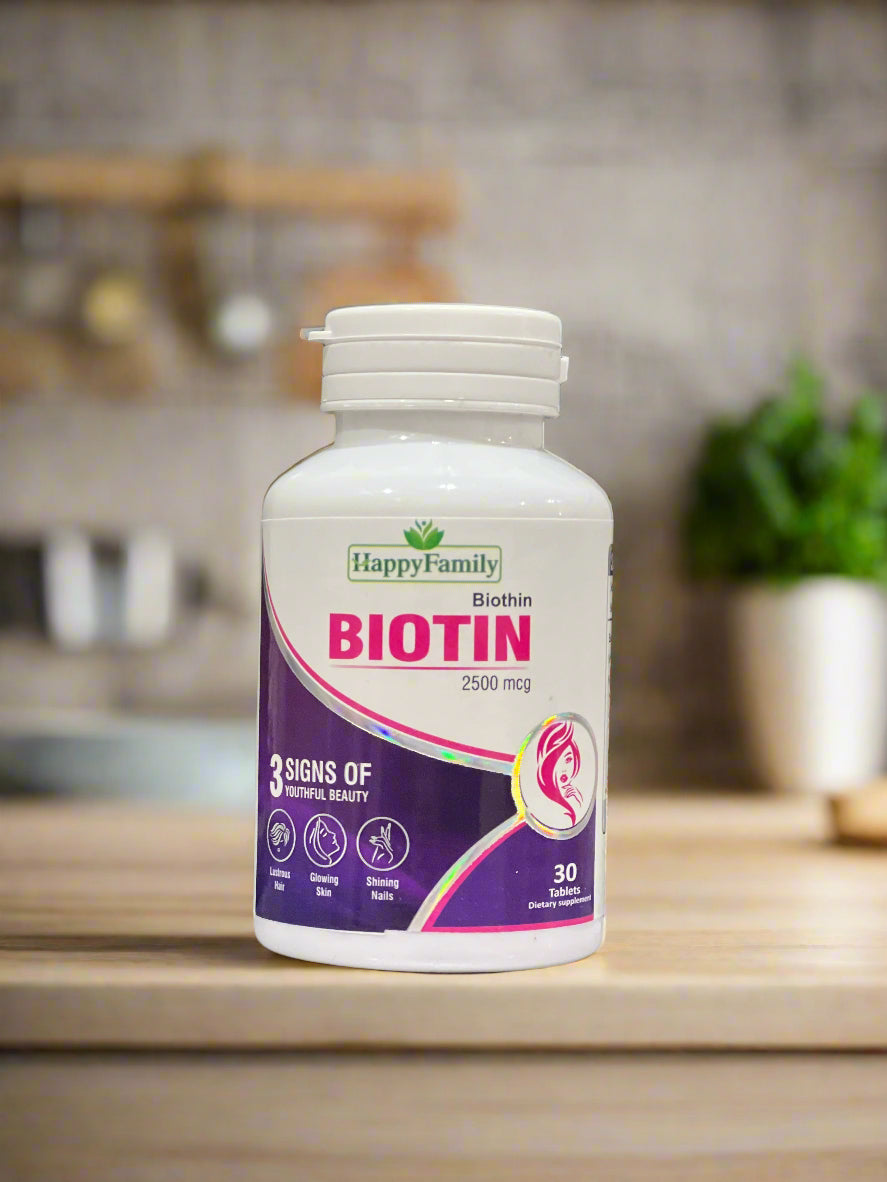 Bottle of Happy Family Biotin supplement on a laptop