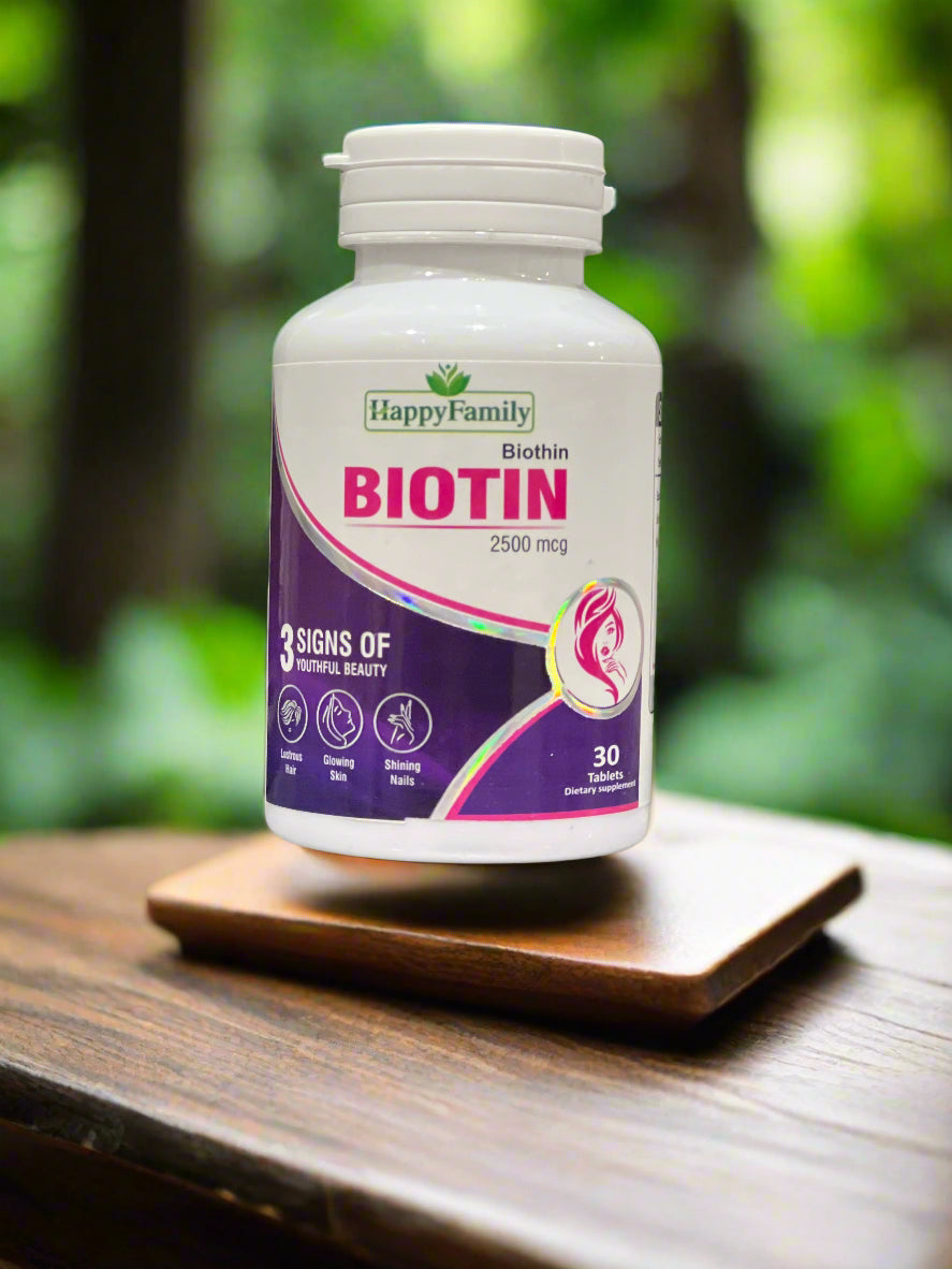 Bottle of Happy Family Biotin supplement on a laptop